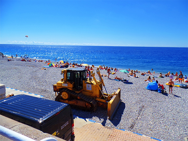 A bulldozer, leveling the pebbles on the beach. Nice, France.